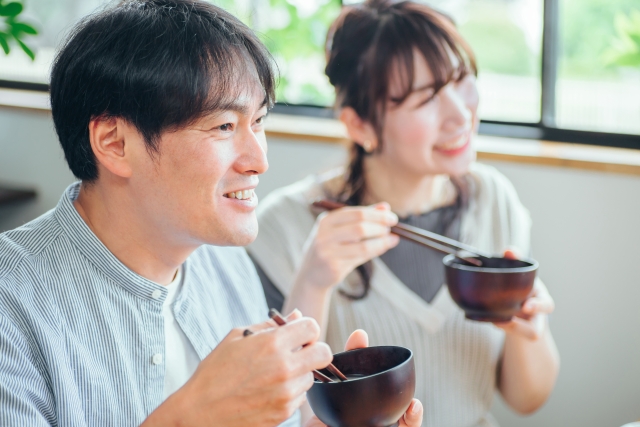 温かい汁ものを飲む男性と女性のイメージ画像